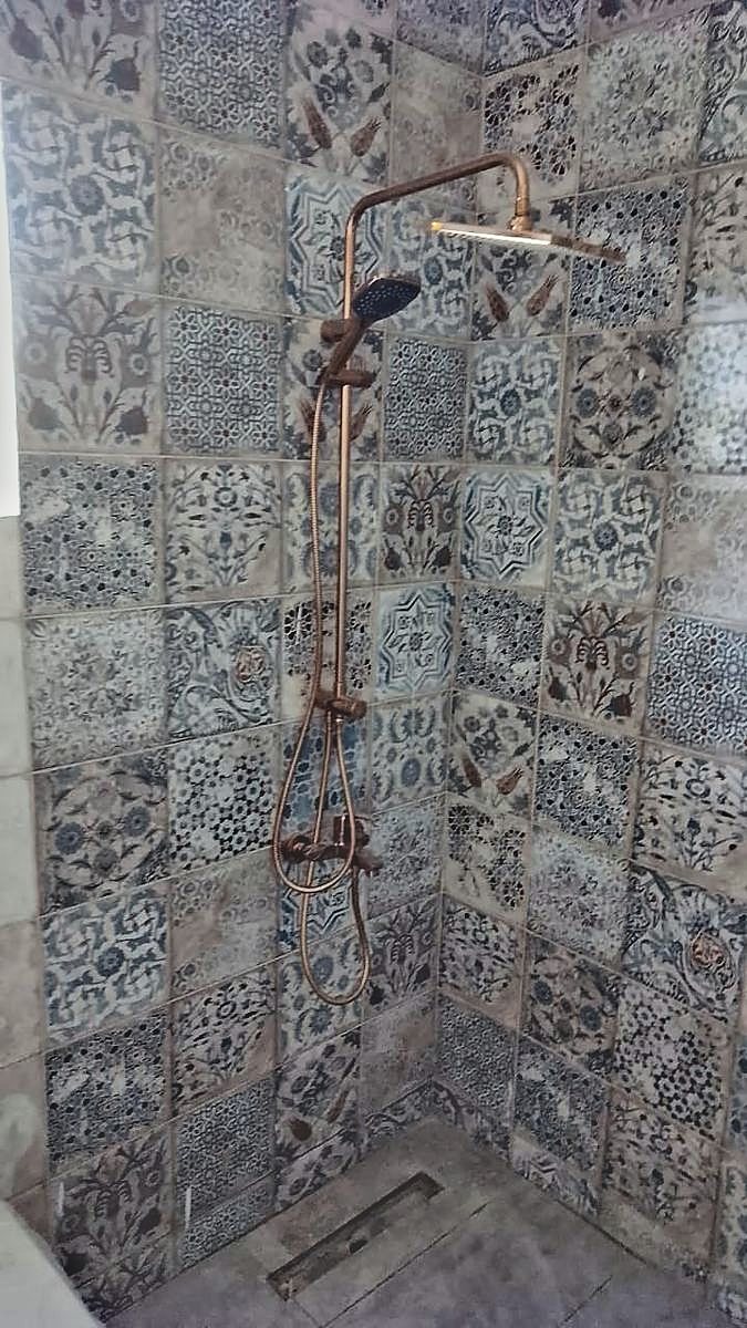 Patterned encaustic-look tile run floor to ceiling in a shower