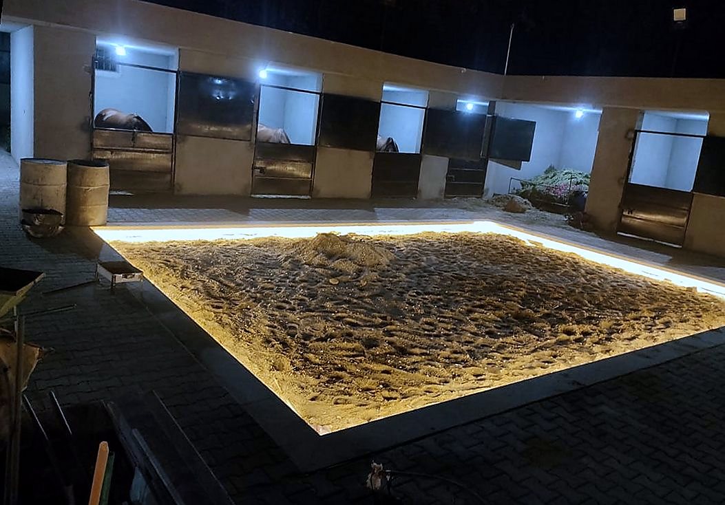 Stable yard at night, the sand bed ringed with a continuous LED strip