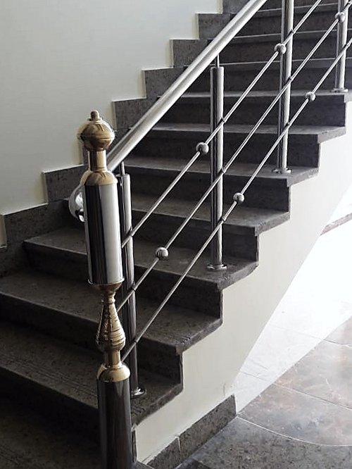 Granite stair with stainless balustrade and brass newel over dark marble