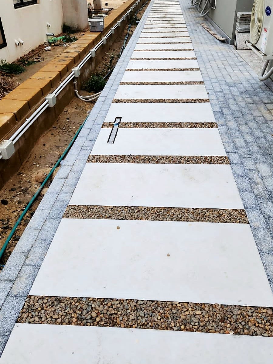Marble walkway with contrasting granite banding through a gravel bed