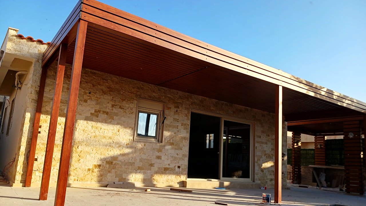 Timber louvre pergola over a pool beside a split-face stone-clad villa