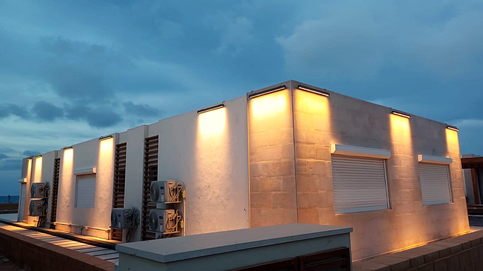 Villa façade at dusk with roller shutters and downlights