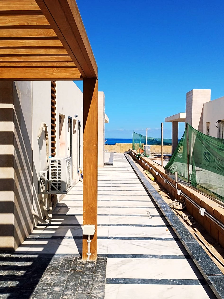 Timber pergola over the marble walkway with the sea beyond