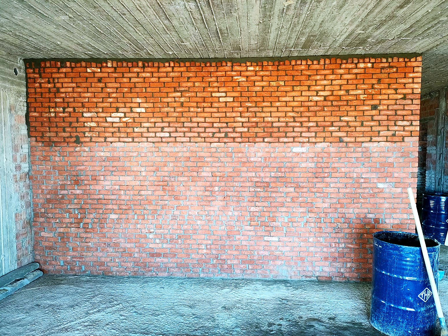 Red brick infill built up tight to the slab soffit — villa shell under construction