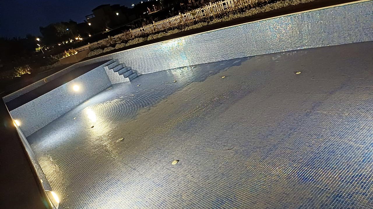 Blue glass mosaic pool lit after dark