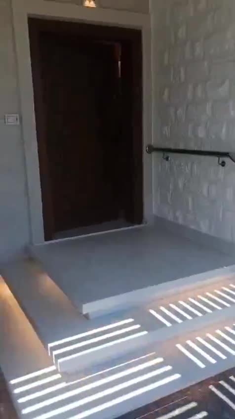 Finished entrance with a wooden door, stone-clad wall and lit steps — on site