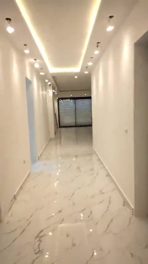 Finished apartment corridor with a cove-lit gypsum ceiling and marble-look floor — on site