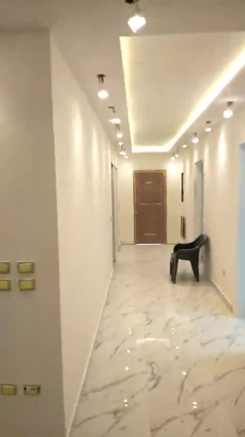 Finished corridor with spotlights, cove lighting and a wooden door at the end — on site