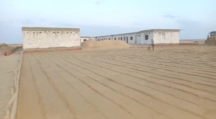 Sand bed being levelled and compacted beside block buildings