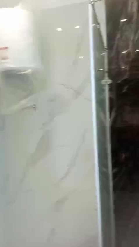 Bathroom with white and dark marble walls and a frameless glass shower